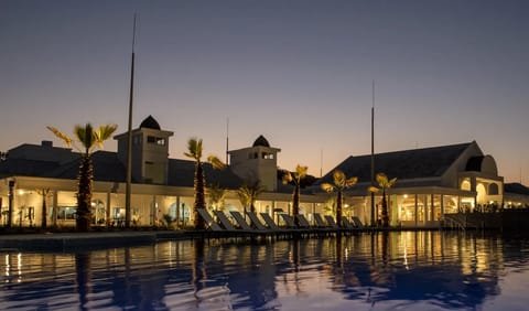 Piscina do Jardins de Jurema iluminada ao anoitecer, com os edifícios refletidos na água