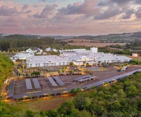 Vista aérea do Jardins de Jurema ao entardecer, com os edifícios brancos cercados de mata
