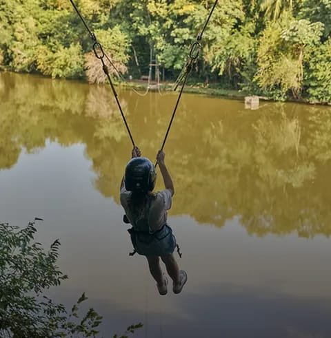 Criança descendo de tirolesa sobre o lago do Lagos de Jurema